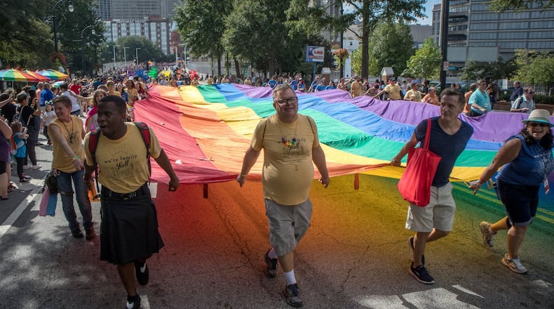 Marchers carry a large rainbow flag up Peachthree Street during Sunday’s Atlanta Pride Parade. STEVE SCHAEFER / SPECIAL TO THE AJC