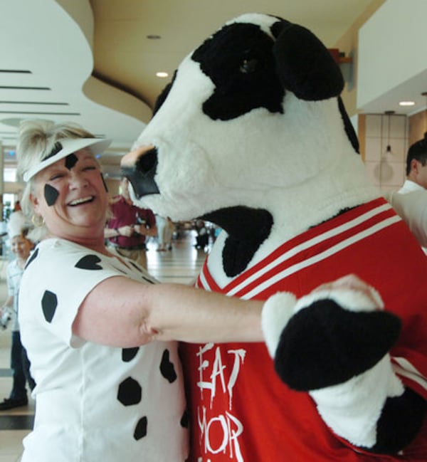 Vinings resident Gillian Greer, properly dressed in cow attire, dances with a Chick-fil-A mascot at Cumberland Mall. (Andy Sharp/AJC file photo)