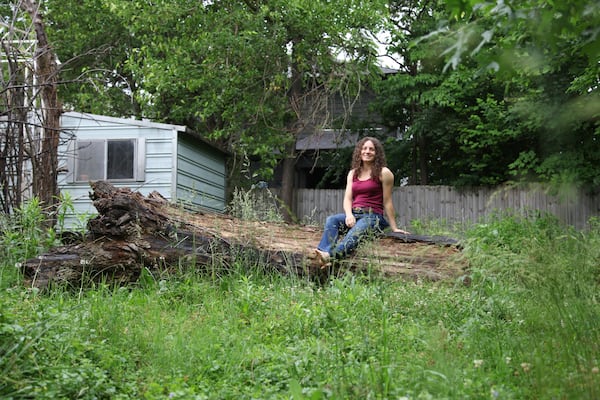 Amanda Beltranmini Healen poses on a fallen log in her backyard in Nashville, Tenn., Monday, May 19, 2025, where she participates in No Mow Months to improve water retention and encourage pollinators. (AP Photo/Kristin M. Hall)