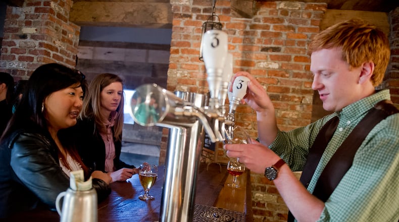 Danny Ritchie (right) pours a beer for Hannah Cho (left) and Natalie Rogol at Three Taverns Craft Brewery in Decatur in this file photo.