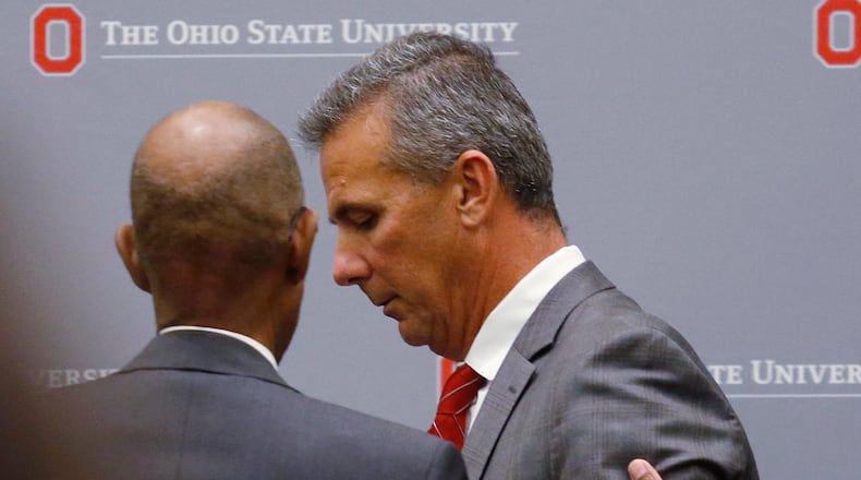 Ohio State University President Michael Drake offers words to football coach Urban Meyer, who leaves the stage following a news conference in Columbus, Ohio, Wednesday, Aug. 22, 2018. (AP Photo/Paul Vernon)