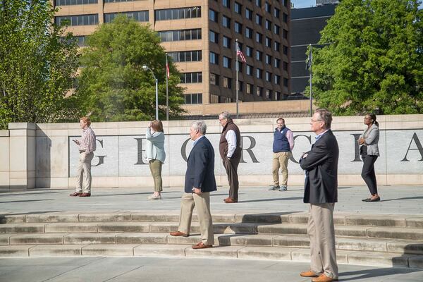 People practice social-distancing as they listen to Gov. Brian Kemp during a press conference Wednesday, April 1, 2020, at Liberty Plaza, across the street from the Georgia State Capitol building in downtown Atlanta. (ALYSSA POINTER / ALYSSA.POINTER@AJC.COM)