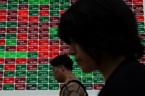 Pedestrians pass by an electronic stock board showing Japan's Nikkei index at a securities firm in Tokyo, Wednesday, June 11, 2025. (AP Photo/Louise Delmotte)