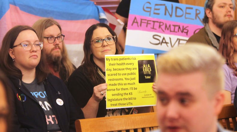 Amanda Mogoi, an advance practice registered nurse who provides care for transgender patients in Wichita, Kan., participates in a protest against a new Kansas law that prevents transgender people from changing their birth certificates and driver's licenses to reflect their gender identities and imposes new, tough enforcement provisions in state restrictions on their bathroom use with a sit-in during a legislative committee hearing, Friday, Feb. 6, 2026, at the Statehouse in Topeka, Kan. (AP Photo/John Hanna)