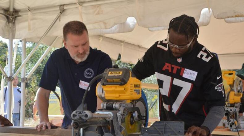 Atlanta Falcons safety Richie Grant uses a power saw, with some guidance from a PlayTown Suwanee volunteer, on Tuesday. Members of the Falcons organization, including some players, came out to help PlayTown Suwanee build its new playground at the Suwanee Town Center on Main. (Photo Courtesy of Curt Yeomans)