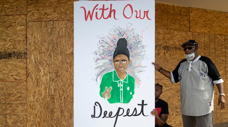 07/07/2020 - Atlanta, Georgia - Bruce W. Griggs, right, holds onto a giant sympathy card for Secoriea Turner's family as a man signs it outside of the All American Package Store in Atlanta's Peoplestown community, Tuesday, July 7, 2020. The card was provided by radio DJ Gregg Street and the OCS Atlanta Street Academy. (ALYSSA POINTER / ALYSSA.POINTER@AJC.COM)