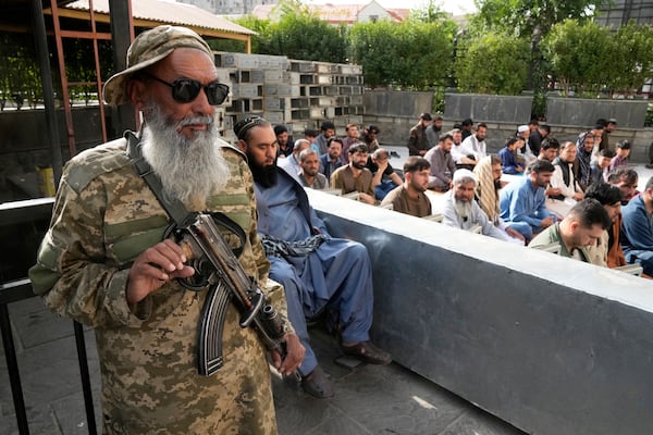 Afghan Muslims perform Eid al-Adha prayer while a Taliban fighter stands guard in the Shah-Do Shamshira Mosque in Kabul, Afghanistan, Saturday, June 7, 2025. (AP Photo/Ebrahim Noroozi)