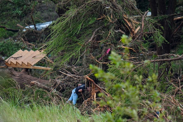 A person searches among debris near the banks of the Guadalupe River after a flash flood swept through the area Saturday, July 5, 2025, in Hunt, Texas. (AP Photo/Julio Cortez)