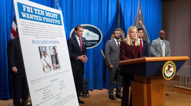 Attorney General Pam Bondi stands near wanted poster for Canadian fugitive Ryan James Wedding as she speaks with reporters during a news conference at the Department of Justice, Wednesday, Nov. 19, 2025, in Washington. (AP Photo/Mark Schiefelbein)