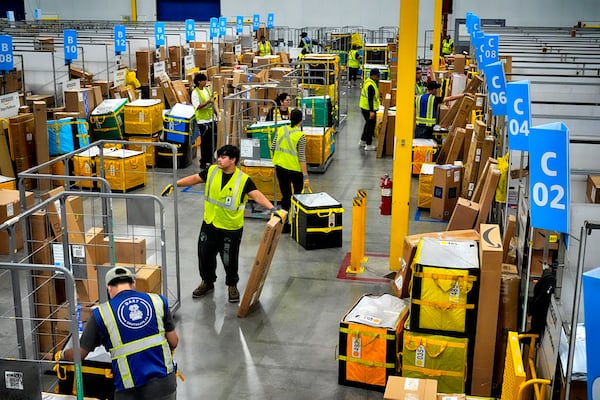 FILE - Amazon employees load packages on carts before being put on to trucks for distribution for Amazon's annual Prime Day event at an Amazon's DAX7 delivery station, July 16, 2024, in South Gate, Calif. (AP Photo/Richard Vogel, File)