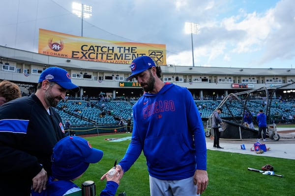 Chicago Cubs shortstop Dansby Swanson, right, signs a ball for a young fan before a baseball game against the Athletics, Monday, March 31, 2025, in West Sacramento, Calif. (AP Photo/Godofredo A. Vásquez)