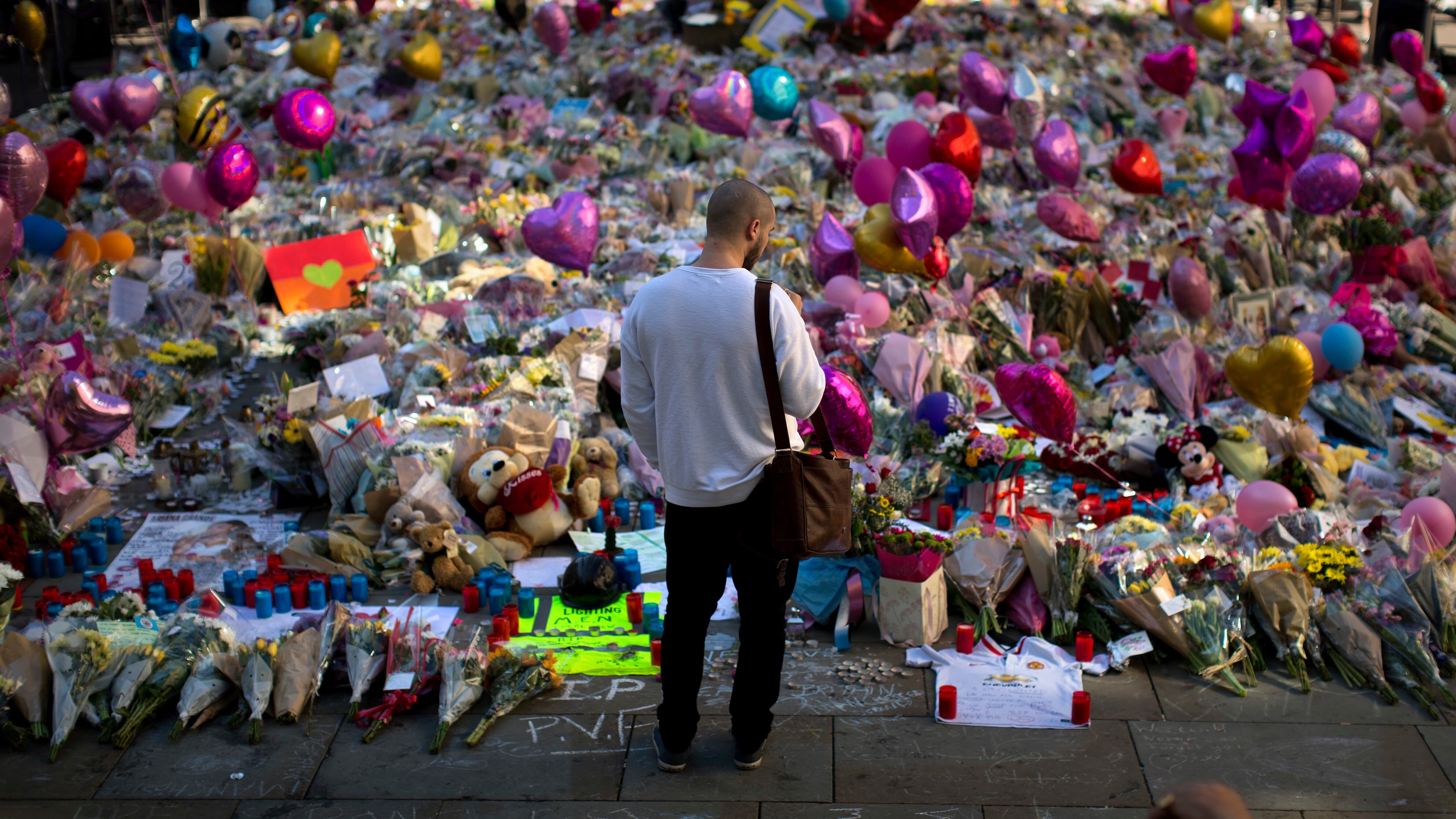 FILE - A man stands next to flowers for the victims of a bombing at St. Ann's Square in central Manchester, England, May 26, 2017. (AP Photo/Emilio Morenatti, File)