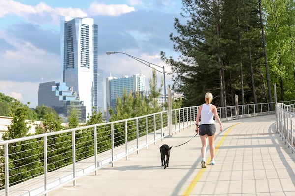 Livable Buckhead’s flagship project is PATH400, a 5.2-mile multi-use trail running through the heart of Buckhead. This photo shows a woman with a ponytail walking her dog on the path. Livable Buckhead emphasizes exercise and outdoor activity, especially during times of social distancing and working from home.