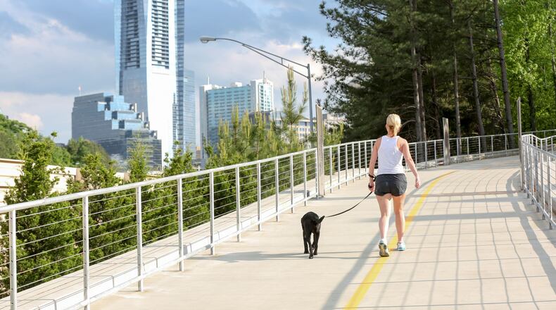 Livable Buckhead’s flagship project is PATH400, a 5.2-mile multi-use trail running through the heart of Buckhead. This photo shows a woman with a ponytail walking her dog on the path. Livable Buckhead emphasizes exercise and outdoor activity, especially during times of social distancing and working from home.