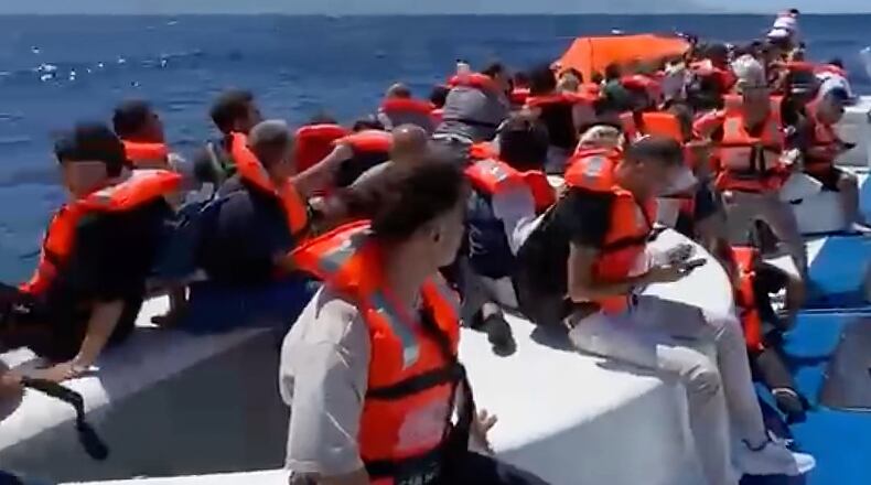 In this frame grab from a video, passengers wearing life jackets wait atop a capsized passenger vessel to be rescued off the coast of Girne, in the Turkish-occupied northern part of Cyprus, Sunday, Aug. 30, 2026. (DHA via AP)