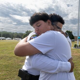 9th grade student, Jose Ortiz-14 (left) is hugged by Georgia State chaplain, Ronald Clark as students and well wishers arrived with flowers to place at the flag pole at Apalachee High School in Winder on Thursday, Sept. 5, 2024. A 14-year-old is accused of shooting and killing two fellow students and two teachers and injuring nine others at Apalachee High School on Wednesday. (John Spink/AJC)