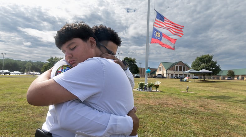 9th grade student, Jose Ortiz-14 (left) is hugged by Georgia State chaplain, Ronald Clark as students and well wishers arrived with flowers to place at the flag pole at Apalachee High School in Winder on Thursday, Sept. 5, 2024. A 14-year-old is accused of shooting and killing two fellow students and two teachers and injuring nine others at Apalachee High School on Wednesday. (John Spink/AJC)