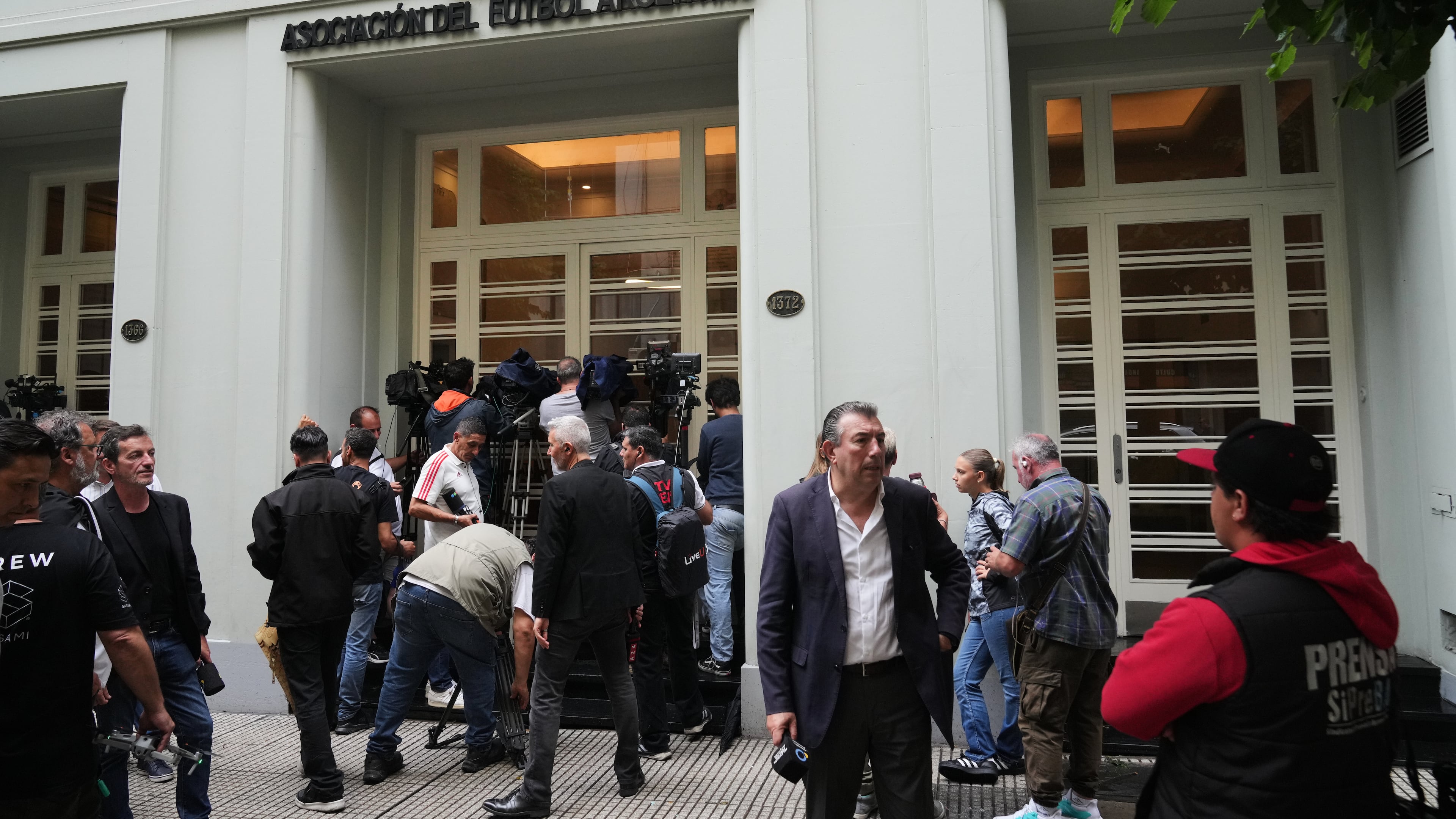 Journalists gather outside the Argentine Soccer Association (AFA) headquarters being raided as part of a judicial investigation into links authorities allege AFA has with a financial services company being investigated for alleged money laundering in Buenos Aires, Argentina, Tuesday, Dec. 9, 2025. (AP Photo/Rodrigo Abd)