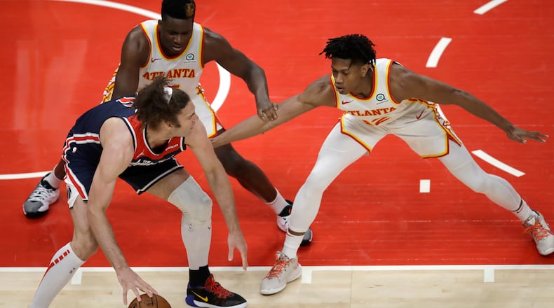 Clint Capela and De'Andre Hunter guard Wizards' Robin Lopez in the second half of an NBA basketball game Monday, May 10, 2021, in Atlanta.