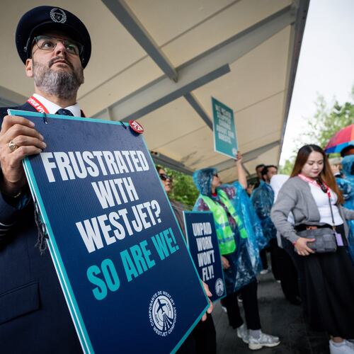 A pilot pickets with WestJet flight attendants on strike at Vancouver International Airport in Richmond, British Columbia, Sunday, Aug. 2, 2026. (Ethan Cairns/The Canadian Press via AP)