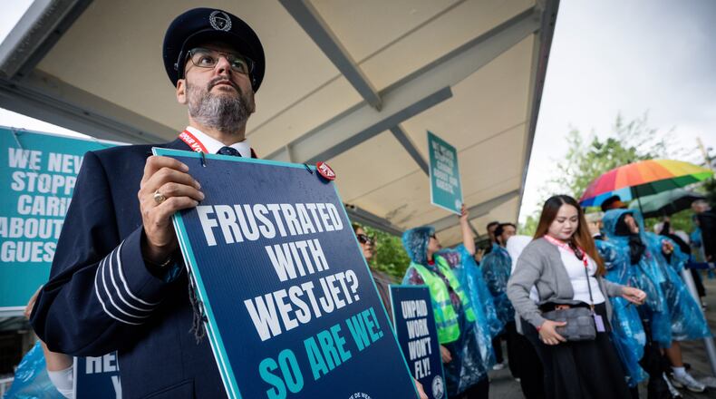A pilot pickets with WestJet flight attendants on strike at Vancouver International Airport in Richmond, British Columbia, Sunday, Aug. 2, 2026. (Ethan Cairns/The Canadian Press via AP)