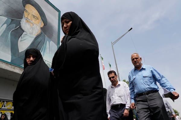 Worshippers walk under a mural of the late Iranian revolutionary founder Ayatollah Khomeini as they leave after the conclusion of the Friday prayer ceremony, in Tehran, Iran, Friday, April 25, 2025. (AP Photo/Vahid Salemi)