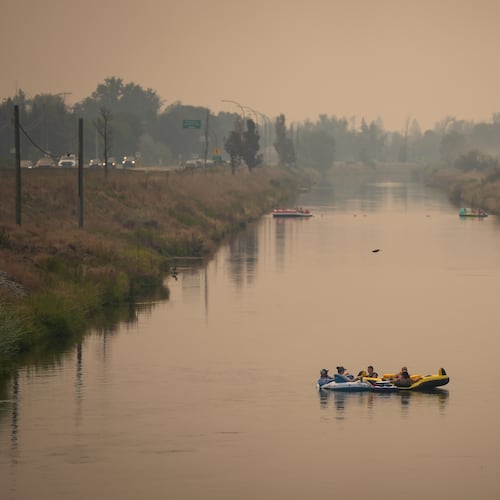 People float on the Channel Pathway that connects Okanagan Lake and Skaha Lake as smoke from wildfires burning in the region fills the air, in Penticton, British Columbia, Monday, Aug. 10, 2026. (Darryl Dyck/The Canadian Press via AP)
