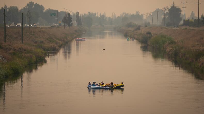 People float on the Channel Pathway that connects Okanagan Lake and Skaha Lake as smoke from wildfires burning in the region fills the air, in Penticton, British Columbia, Monday, Aug. 10, 2026. (Darryl Dyck/The Canadian Press via AP)