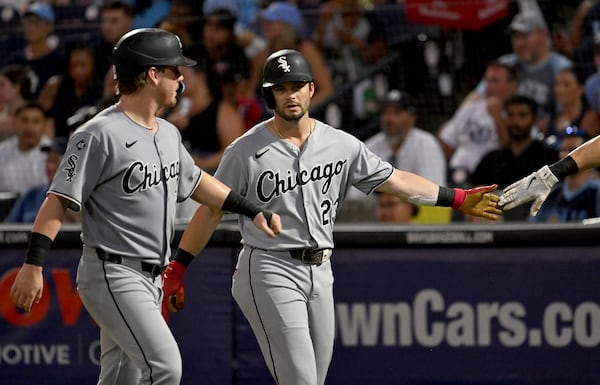 Chicago White Sox's Chase Meidroth, left, and Andrew Benintendi (23) celebrate after scoring on a single by Luis Robert Jr. during the third inning of a baseball game Monday, July 21, 2025, in Tampa, Fla. (AP Photo/Jason Behnken)