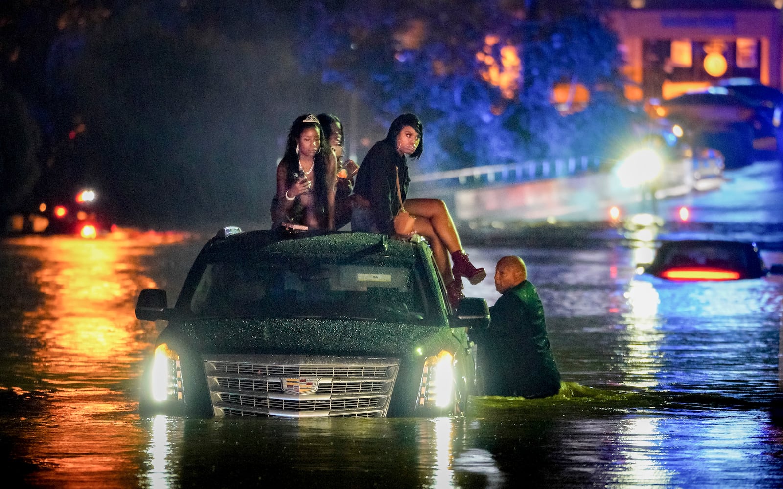 A Sept. 7 storm deluged parts of Cobb, Fulton, Gwinnett and Forsyth counties with several inches of rainfall over 24 hours. In this photos, a limousine driver stands in floodwaters as his passengers take shelter on the roof. Multiple vehicles stalled on Delk road amid rising flood waters. Ben Hendren for the AJC