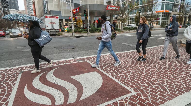 Georgia State University students walk to their classes on Dec. 5, 2022. The school created a grant program to help students struggling to pay their tuition complete their degrees. Some higher education advocates want state leaders to offer more support for students facing similar challenges. (John Spink / John.Spink@ajc.com)