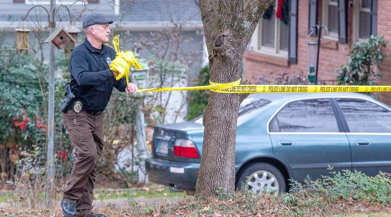 A Doraville police officer takes down the crime scene tape at a home on Beachwood Avenue where a 43-year-old man was discovered shot and killed early Thursday morning.