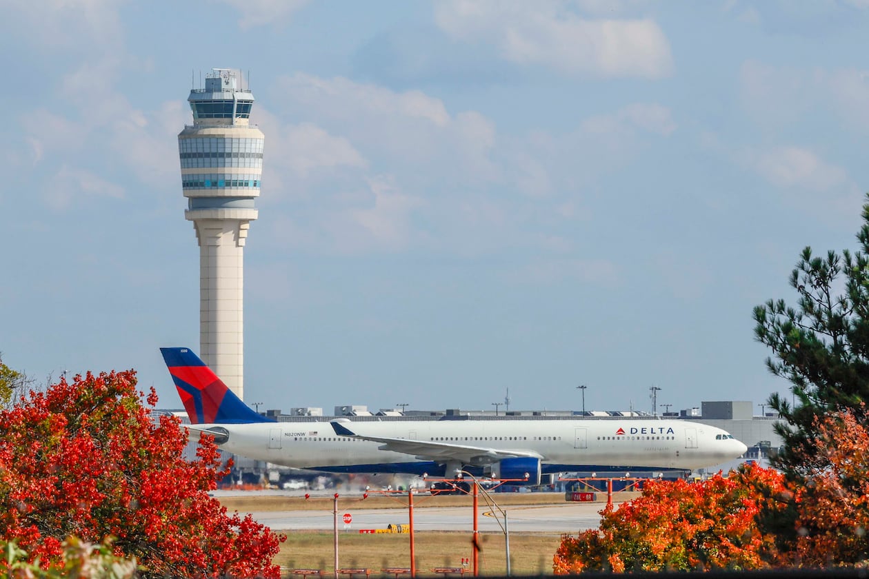 A Delta Air Lines plane passes by the control tower at Hartsfield-Jackson Atlanta International Airport on Sunday, Nov. 9, 2025. Transportation Secretary Sean Duffy warned Friday that flight reductions might continue to increase if the government shutdown persists. (Miguel Martinez/AJC)