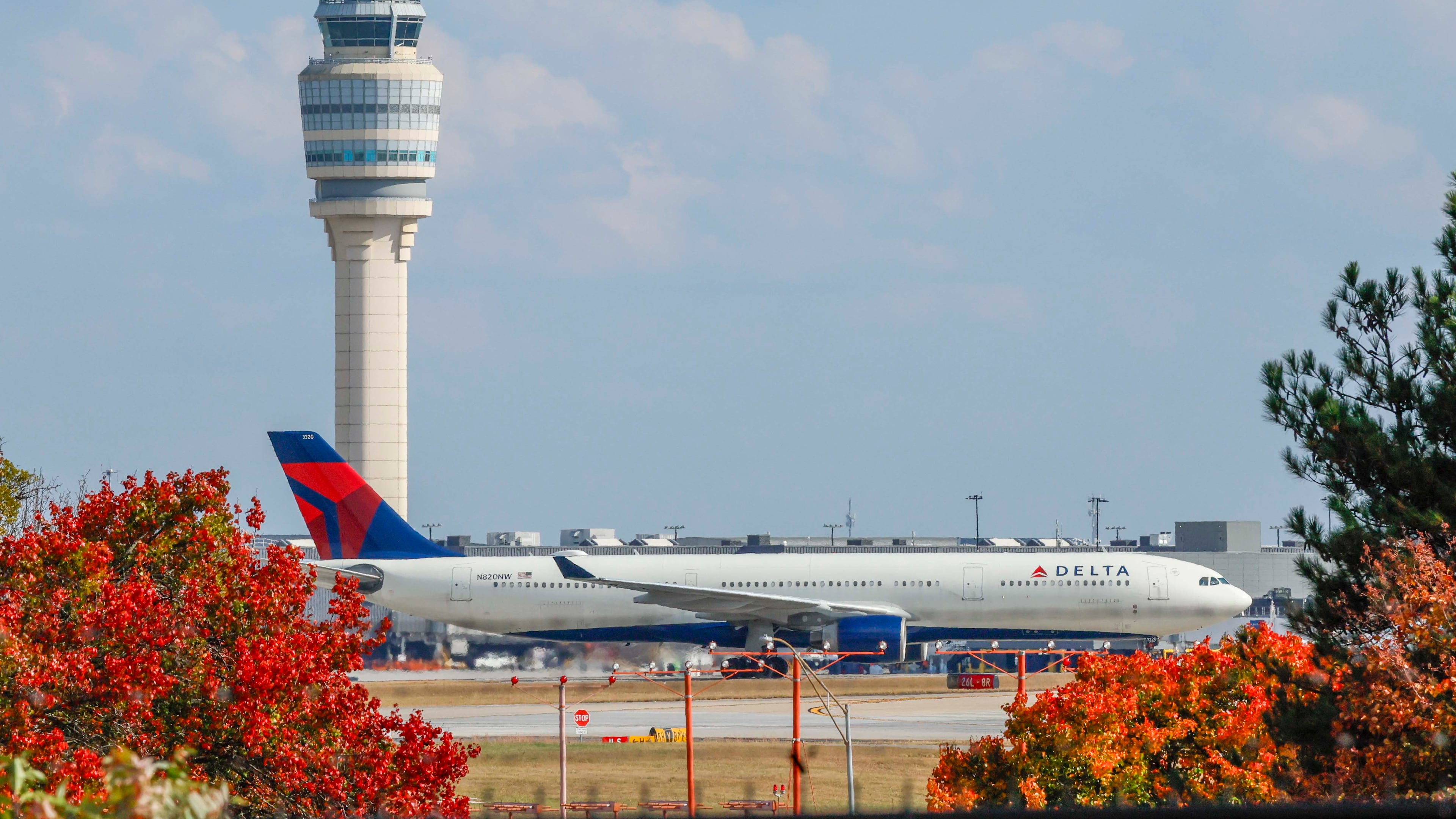 A Delta Air Lines plane passes by the control tower at Hartsfield-Jackson Atlanta International Airport on Sunday, Nov. 9, 2025. Transportation Secretary Sean Duffy warned Friday that flight reductions might continue to increase if the government shutdown persists. (Miguel Martinez/AJC)