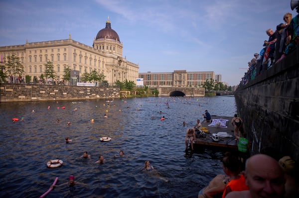 People swim in the river Spree to demand the lift of the hundred years old swimming ban at the river in front of the Stadtschloss or City Place in Berlin, Germany, Tuesday, June 17, 2025. (AP Photo/Markus Schreiber)