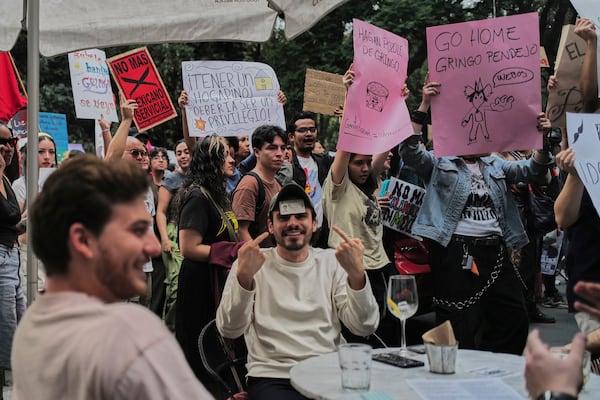 A man points to his Mexican ID to prove his nationality as people protest against gentrification, as the increase in remote workers has risen prices and increased housing demand in neighborhoods like Condesa and Roma, in Mexico City, Friday, July 4, 2025. (AP Photo/Jon Orbach)