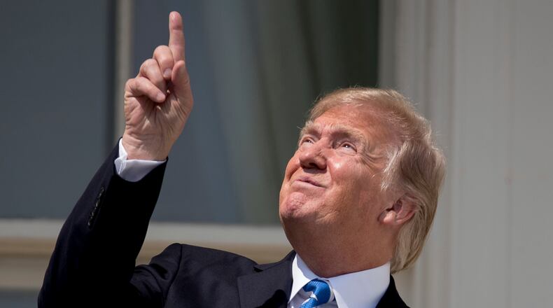 President Donald Trump points to the sun as he arrives to view the solar eclipse, Monday, Aug. 21, 2017, at the White House in Washington. (AP Photo/Andrew Harnik)