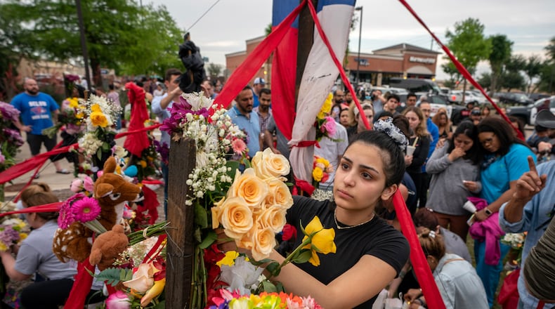 Jessel Paredes, 16, places flowers Sunday on a memorial outside the Allen Premium Outlets in suburban Dallas, where, a day before, a gunman killed eight. The shooter's social media posts indicate that he had staked out the mall using Google to determine the busiest times. CREDIT: The Washington Post by Jeffrey McWhorter