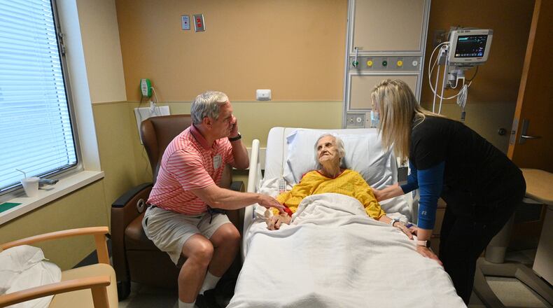 Bill Collins holds the hand of his mother, Edith Collins, as Candice Wade (right), a registered nurse, checks on her at the cardiovascular unit of the Northeast Georgia Medical Center in Gainesville. (Hyosub Shin / Hyosub.Shin@ajc.com)