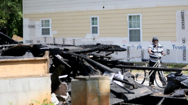 Bobby Woodall walks his bike past the burnt-out remains of one of Buckhead investor Rick Warren’s properties in Northwest Atlanta on Thursday afternoon. Ben Gray / bgray@ajc.com