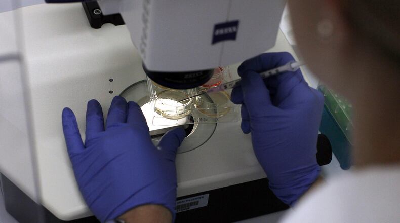 A scienitst studies stem cells under a microscope.