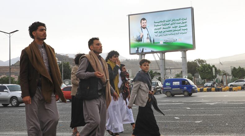 People walk under a billboard showing Houthi leader Abdul Malik al-Houthi with a phrase from the Islamic book Quran that reads in Arabic; "In the bounty of Allah and in His mercy - in that let them rejoice; it is better than what they accumulate" in Sanaa, Yemen, Sunday, Sept. 6, 2026. (AP Photo/Osamah Abdulrahman)
