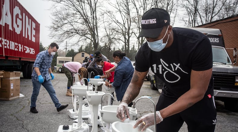 Hip-hop recording artist Lecrae assembles a portable washing station on Thursday, March 19, 2020, in College Park. Lecrae reached out to Love Beyond Walls, a nonprofit led by Terence Lester, to offer assistance, and he donated money for the first 15 washing stations, which are for the use of homeless people in the Atlanta area. AP PHOTO/ RON HARRIS