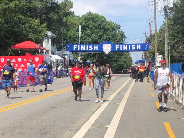 Final groups of racers crossing finish line of Atlanta Journal-Constitution Peachtree Road Race late morning Monday, July 4, 2022 in Atlanta.