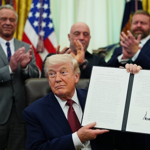 President Donald Trump holds up a signed executive order in the Oval Office of the White House, Saturday, April 18, 2026, in Washington. (AP Photo/Julia Demaree Nikhinson)
