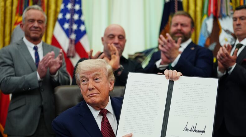 President Donald Trump holds up a signed executive order in the Oval Office of the White House, Saturday, April 18, 2026, in Washington. (AP Photo/Julia Demaree Nikhinson)