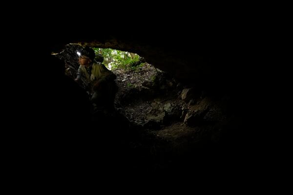 Takamatsu Gushiken, a "gamafuya," an Okinawa dialect meaning a person who digs in a cave, looks at the wall of a cave while searching for the remains of those who died during the Battle of Okinawa towards the end of the World War II in 1945, in Itoman, on the main island of the Okinawa archipelago, southern Japan, Saturday, Feb. 15, 2025. (AP Photo/Hiro Komae)