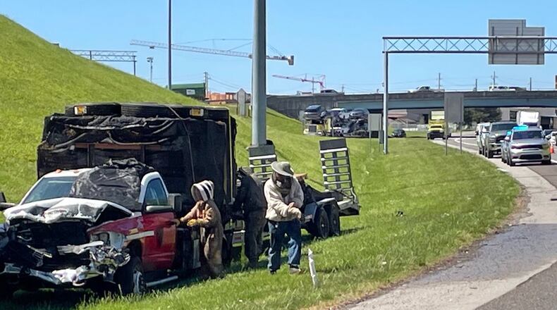 In this photo provided by the Tennessee Department of Transportation, beekeepers work to contain a swarm of bees that escaped from a crashed truck on Interstate 40 in Knoxville, Tenn., on Friday, April 17, 2026. (TDOT via AP)