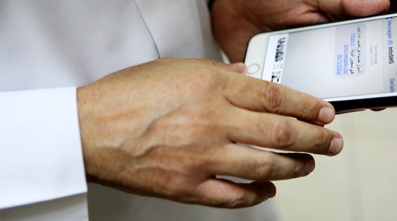 Human rights activist Ahmed Mansoor shows Associated Press journalists a screenshot of a spoof text message he received in Ajman, United Arab Emirates, on Thursday, Aug. 25, 2016. Mansoor was recently targeted by spyware that can hack into Apple's iPhone handset. The company said Thursday it was updated its security. The text message reads: "New secrets on the torture of Emirati citizens in jail." (AP Photo/Jon Gambrell)