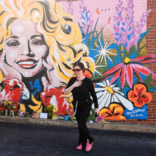 Katie Greene visits a mural of Dolly Parton on Tuesday, Aug. 25, 2026, in Nashville, Tenn. Parton did not like talking about her politics, but she spoke her values through her words and actions, AJC opinion editor David Plazas writes. (George Walker IV/AP)